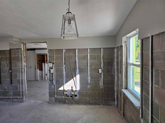 interior space featuring a textured ceiling, concrete floors, lofted ceiling, and a healthy amount of sunlight