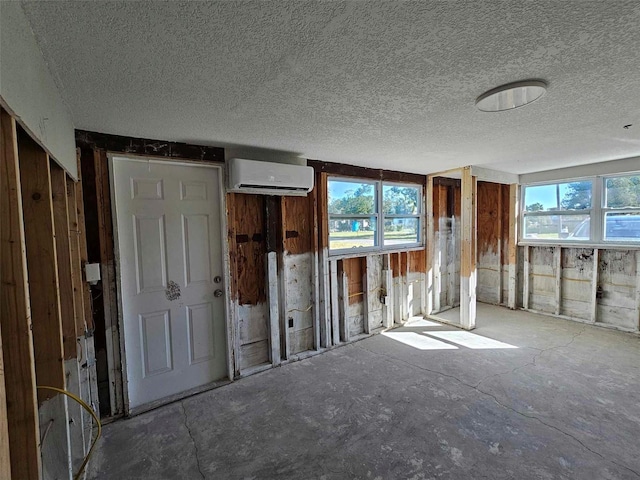 interior space featuring a wall mounted air conditioner and a textured ceiling