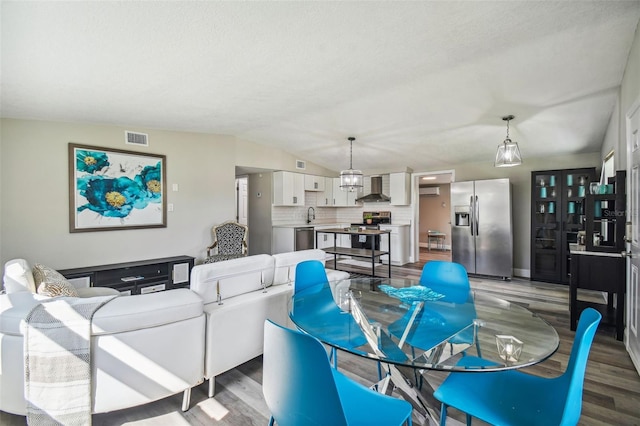 living room with a textured ceiling, hardwood / wood-style flooring, lofted ceiling, and sink