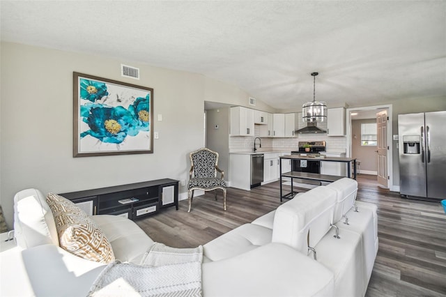 living room with sink, vaulted ceiling, dark hardwood / wood-style floors, a textured ceiling, and a chandelier