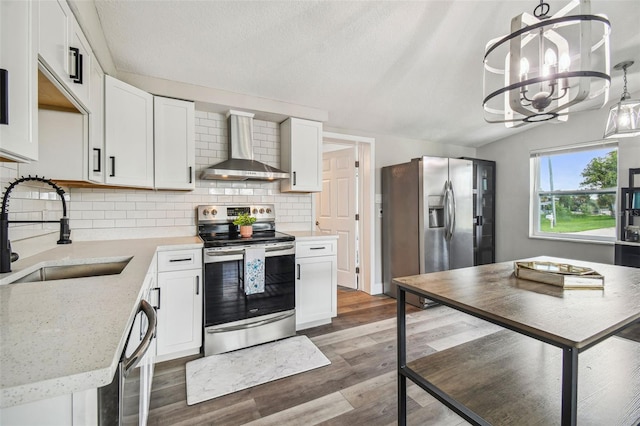 kitchen featuring white cabinets, wall chimney range hood, sink, a notable chandelier, and stainless steel appliances