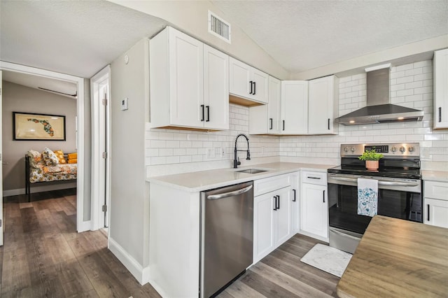 kitchen featuring white cabinets, sink, wall chimney exhaust hood, and appliances with stainless steel finishes