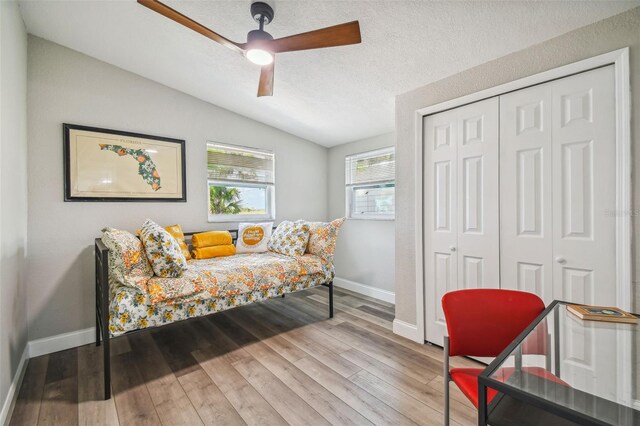 bedroom featuring ceiling fan, hardwood / wood-style floors, a textured ceiling, lofted ceiling, and a closet