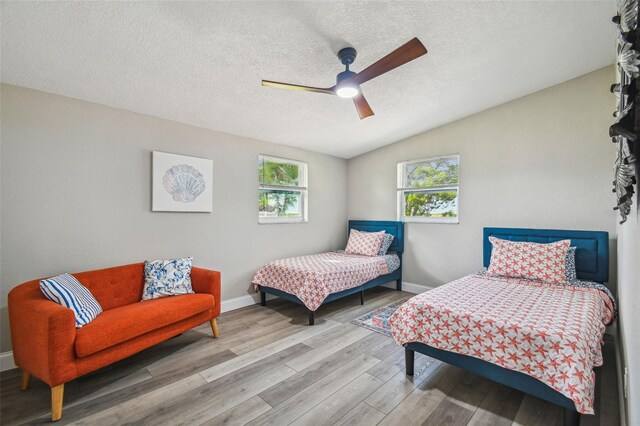 bedroom featuring wood-type flooring, a textured ceiling, ceiling fan, and lofted ceiling