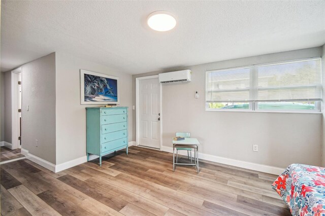 interior space with an AC wall unit, light hardwood / wood-style flooring, and a textured ceiling