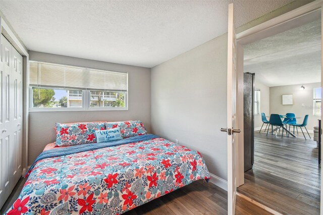 bedroom with a textured ceiling, dark wood-type flooring, and a closet