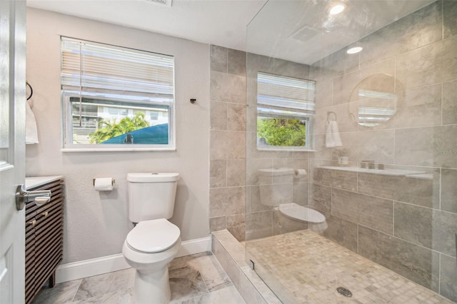 bathroom with a tile shower and toilet