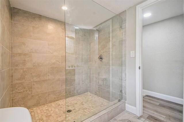 bathroom featuring hardwood / wood-style flooring and a tile shower