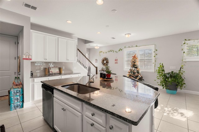 kitchen featuring dishwasher, sink, a healthy amount of sunlight, and an island with sink