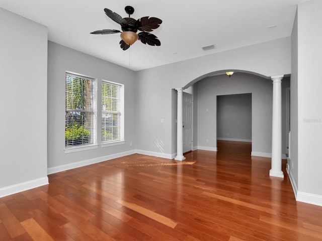 unfurnished room featuring hardwood / wood-style flooring, ornate columns, and ceiling fan