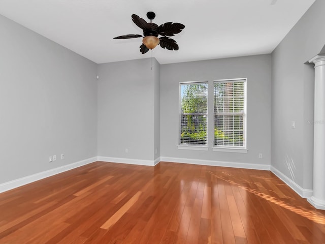 spare room featuring wood-type flooring, ornate columns, and ceiling fan