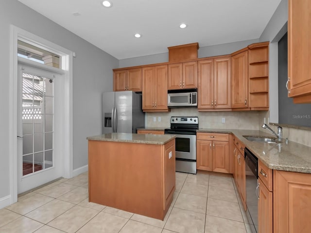 kitchen featuring decorative backsplash, appliances with stainless steel finishes, light stone counters, sink, and a kitchen island