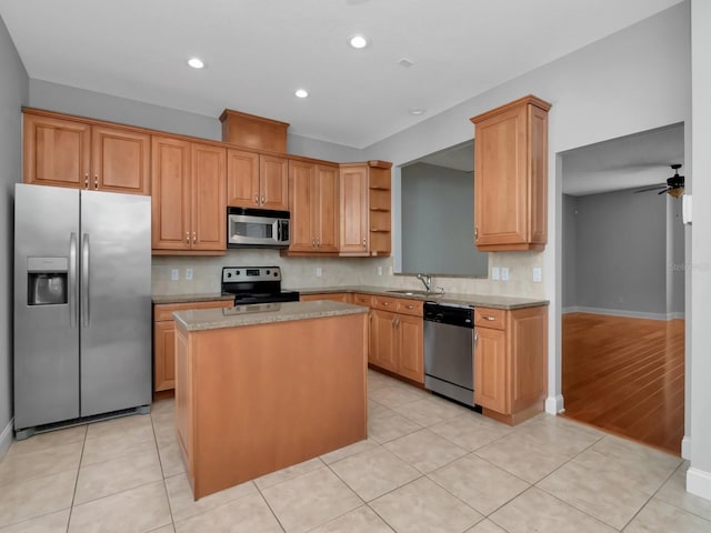 kitchen with sink, ceiling fan, light wood-type flooring, appliances with stainless steel finishes, and a kitchen island