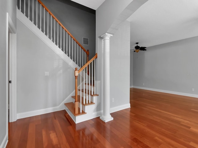 staircase with ornate columns, ceiling fan, and hardwood / wood-style flooring