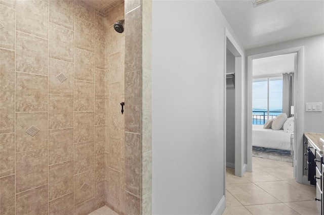 bathroom with tile patterned flooring, vanity, and tiled shower