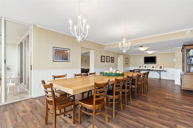 dining space featuring ornamental molding, dark wood-type flooring, and an inviting chandelier