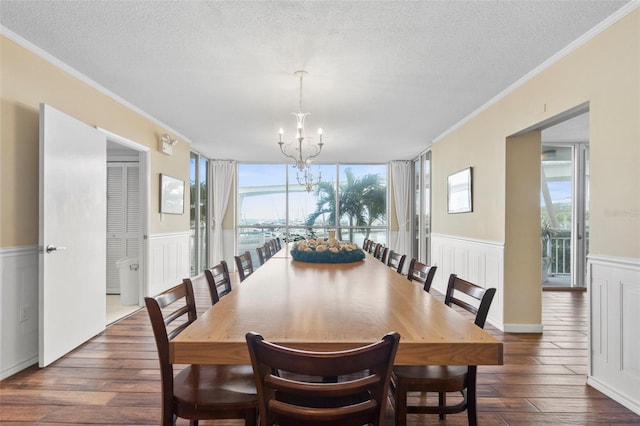 dining room with dark hardwood / wood-style flooring, ornamental molding, a textured ceiling, and an inviting chandelier