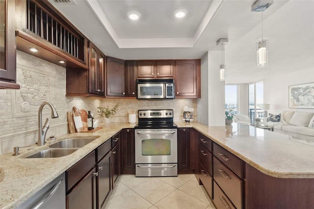 kitchen featuring tasteful backsplash, stainless steel appliances, a raised ceiling, sink, and hanging light fixtures