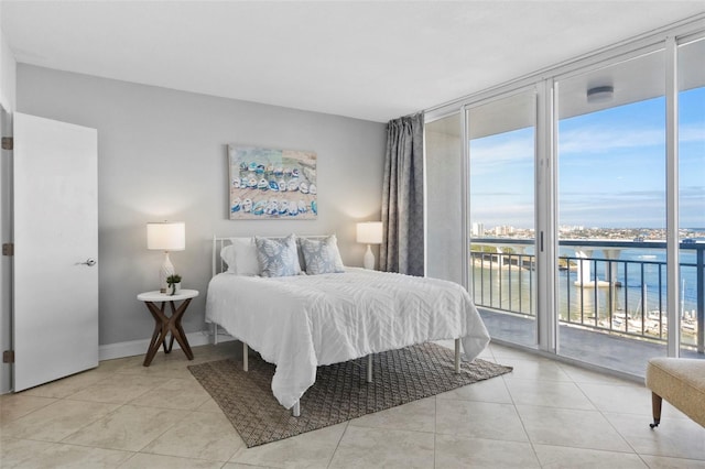 tiled bedroom featuring access to outside, a water view, and floor to ceiling windows