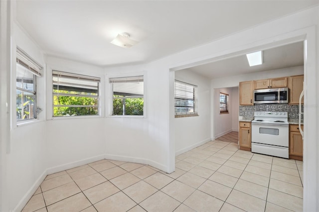 kitchen with white range with electric stovetop, decorative backsplash, light brown cabinetry, and light tile patterned floors