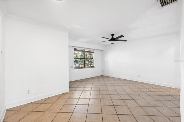 tiled empty room with ceiling fan and ornamental molding