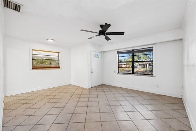 tiled empty room with ornamental molding, ceiling fan, and a healthy amount of sunlight