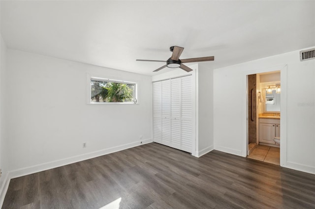 unfurnished bedroom featuring ceiling fan, a closet, ensuite bathroom, and dark hardwood / wood-style floors