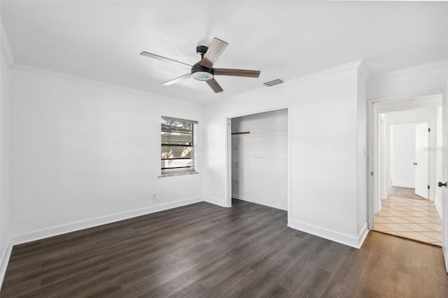 unfurnished bedroom featuring ceiling fan, crown molding, dark wood-type flooring, and a closet