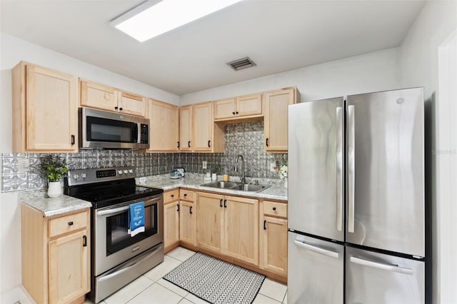 kitchen featuring light brown cabinets, stainless steel appliances, light countertops, and a sink