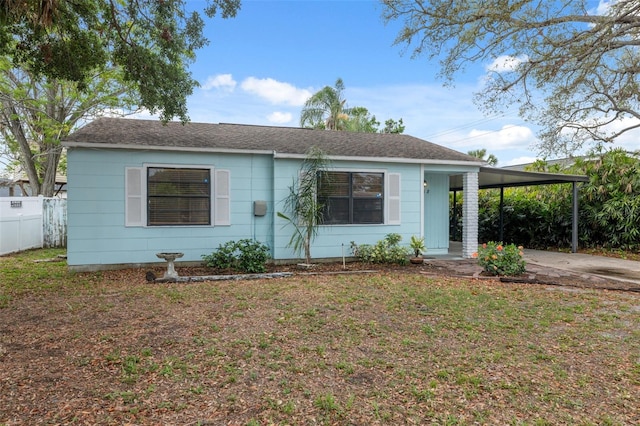 view of front of property featuring fence, a front lawn, and an attached carport