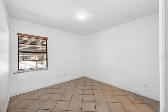 empty room with baseboards and light tile patterned floors