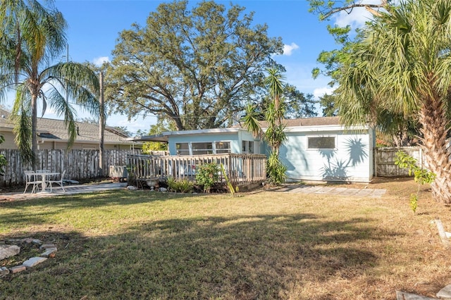 rear view of house with a lawn, fence, and a deck