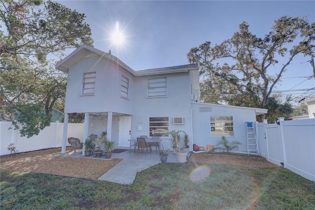 back of property with a yard, a patio, and a wall mounted AC