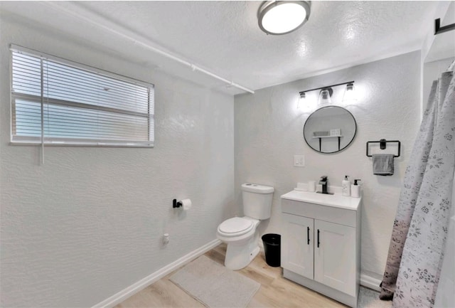 bathroom with hardwood / wood-style flooring, vanity, toilet, and a textured ceiling