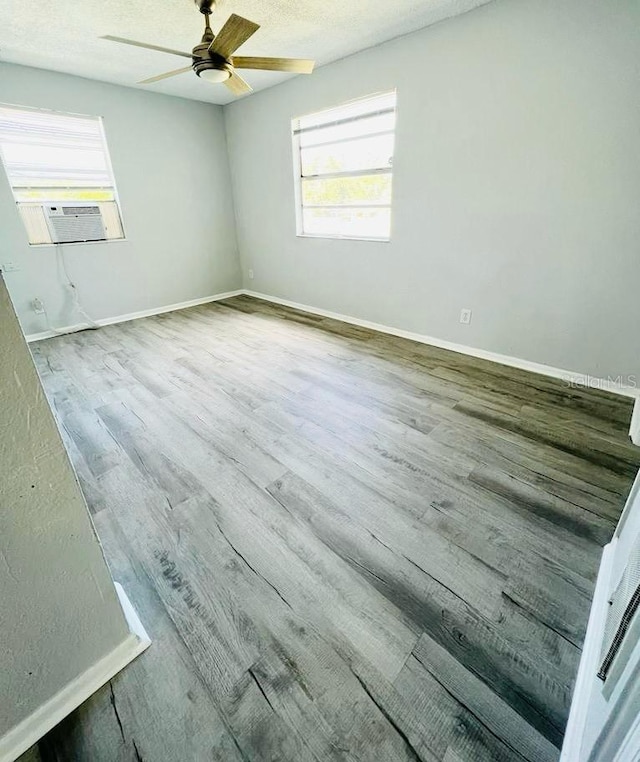 spare room featuring hardwood / wood-style flooring, ceiling fan, cooling unit, and a textured ceiling