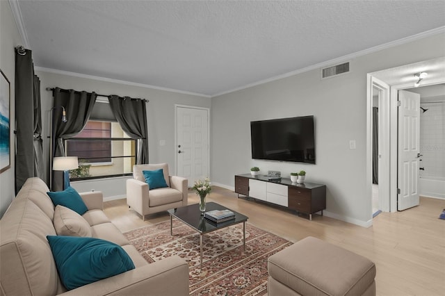 living room with light hardwood / wood-style floors, a textured ceiling, and ornamental molding