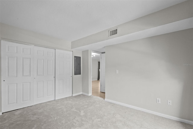 unfurnished bedroom featuring light colored carpet, electric panel, and a closet