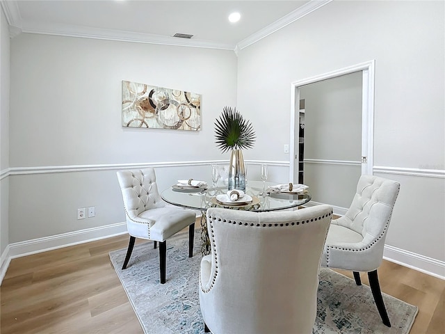 dining room with crown molding and hardwood / wood-style flooring