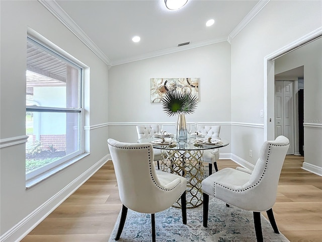 dining room with crown molding, vaulted ceiling, and light wood-type flooring