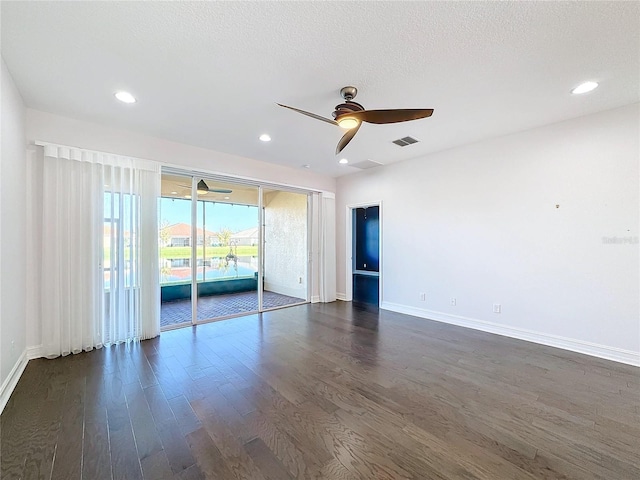 empty room featuring a textured ceiling, ceiling fan, and dark wood-type flooring