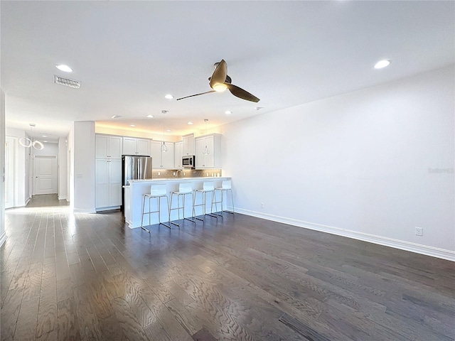 unfurnished living room featuring ceiling fan and dark hardwood / wood-style flooring