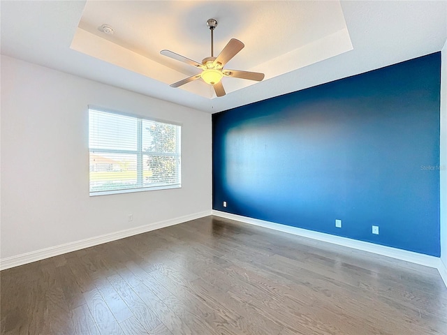 spare room with hardwood / wood-style floors, ceiling fan, and a tray ceiling