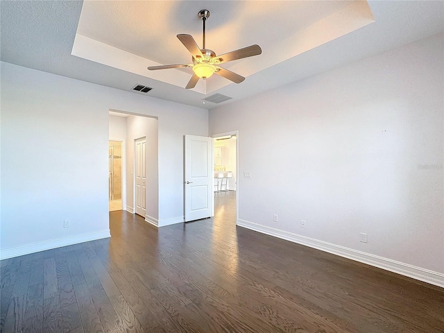 unfurnished bedroom with a raised ceiling, ceiling fan, and dark wood-type flooring