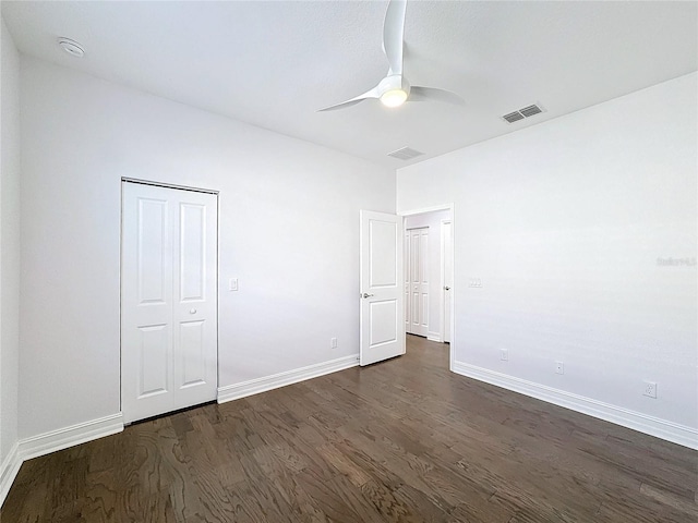 unfurnished bedroom with ceiling fan, dark wood-type flooring, and a closet