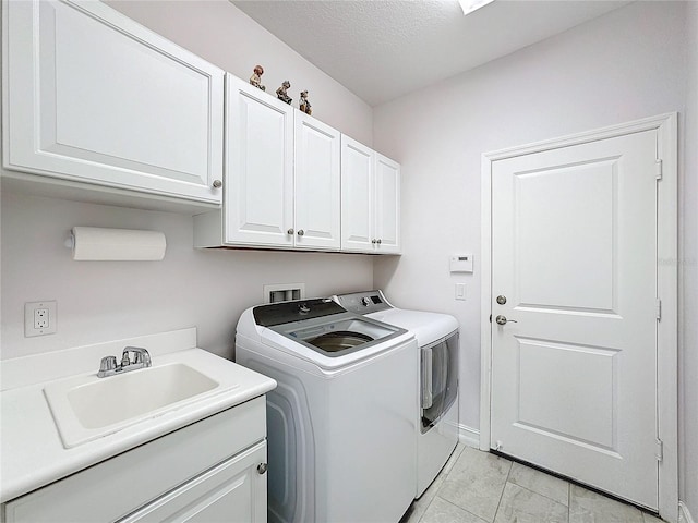 laundry area featuring a textured ceiling, washer and dryer, cabinets, and sink