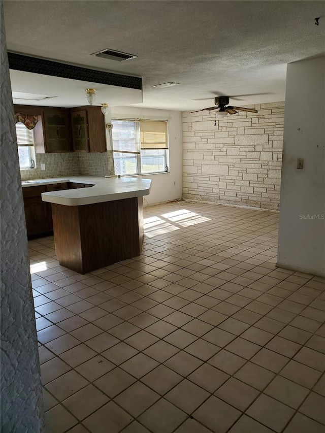 kitchen with brick wall, tasteful backsplash, a wealth of natural light, and ceiling fan