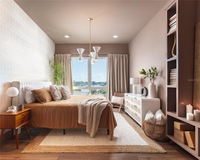 bedroom featuring wood-type flooring, a water view, and an inviting chandelier