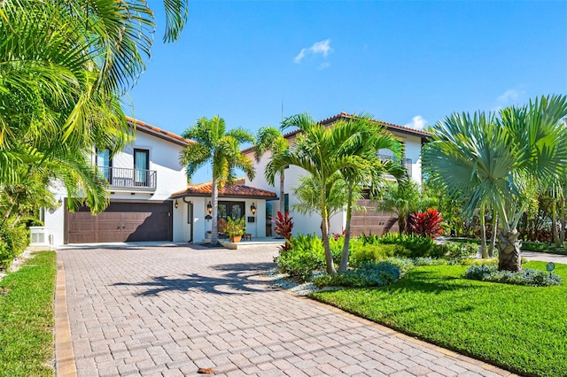 mediterranean / spanish home with a balcony, a front yard, and a garage