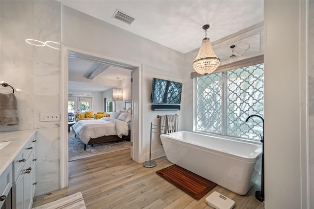 bathroom featuring vanity, hardwood / wood-style flooring, a bathtub, and a notable chandelier