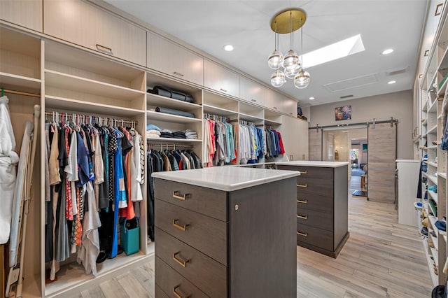 spacious closet featuring a barn door and light hardwood / wood-style flooring